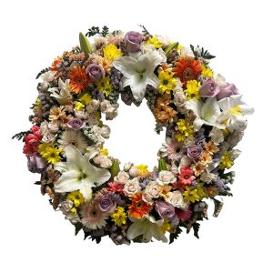 Corona de flores variadas en tonos claros con toques naranjas y malvas